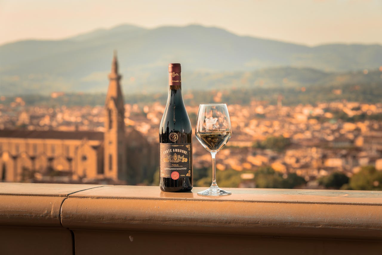 about-us-01 Wine bottle and glass with Tuscan town and landscape, evoking warmth and elegance.
