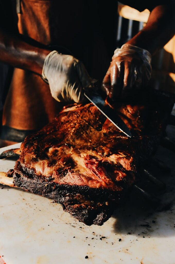 pexels-photo-2491272 A skilled chef slices roasted steak on a barbecue grill, showcasing culinary expertise and deliciousness.